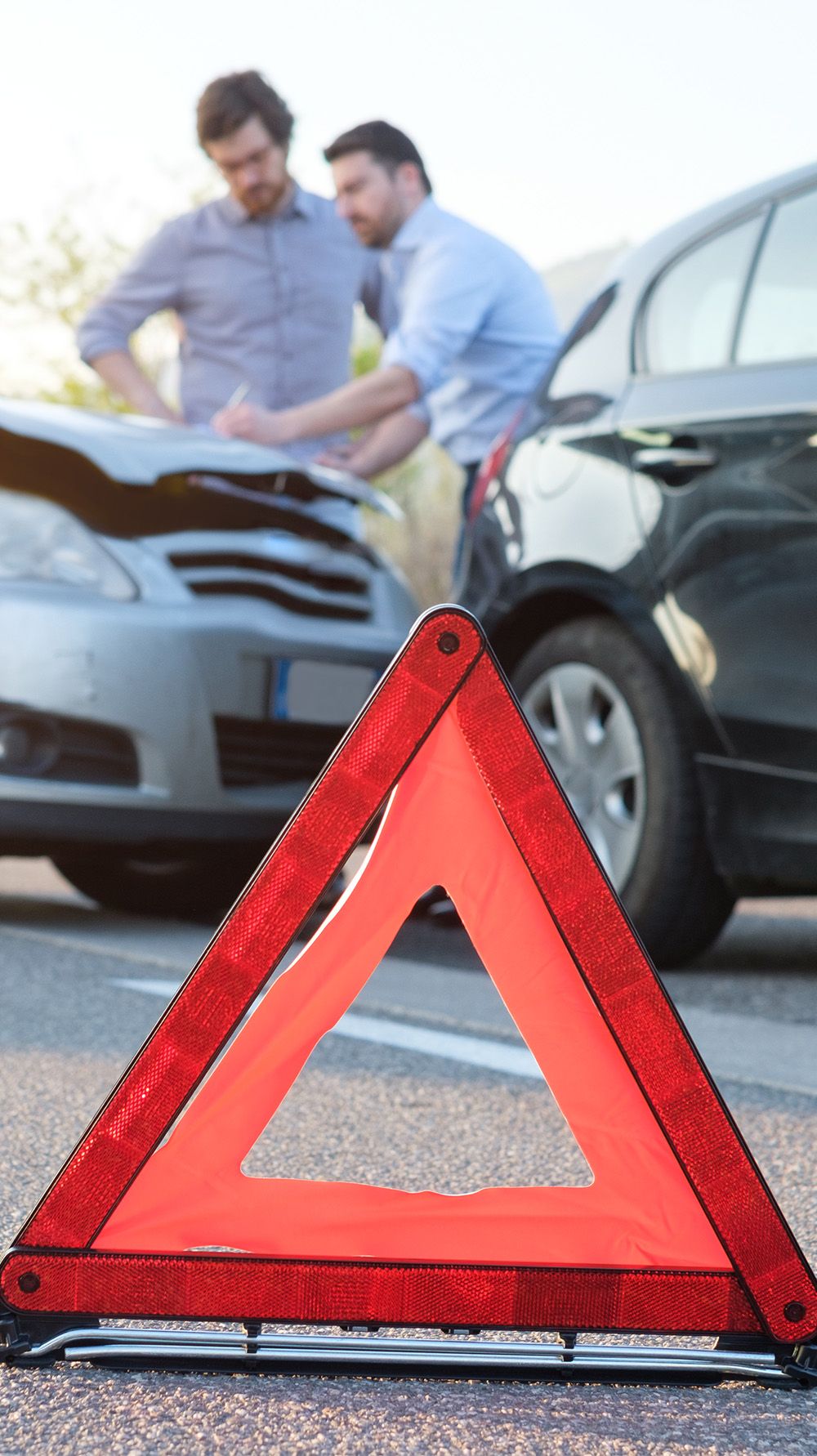 Ansicht eines Unfalls mit aufgestelltem Warndreieck im Vordergrund